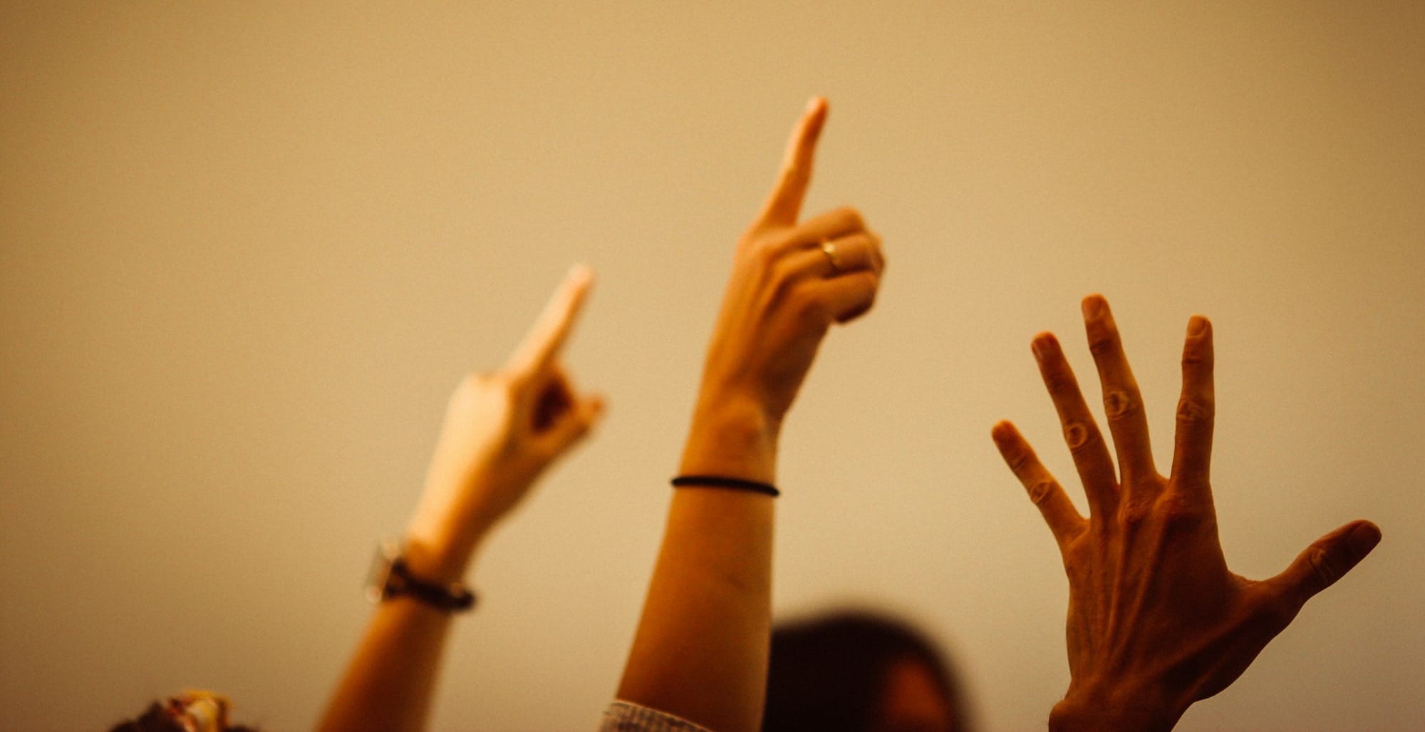 person in black long sleeve shirt raising right hand