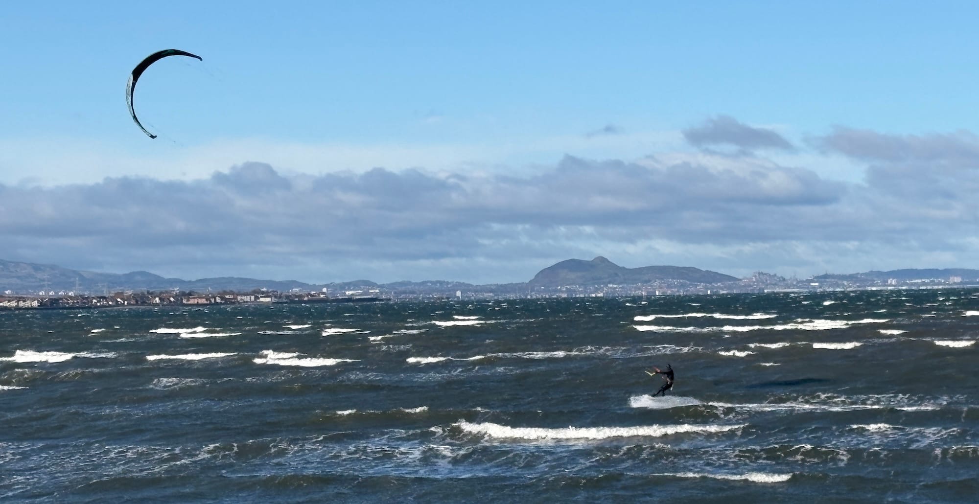 A kite surfer in front of the Edinburgh skyline